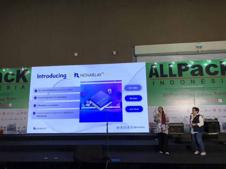 IMG_1602 - Hovarlay Stage at a trade show with a large screen reading 'Introducing R HOVARLAY', two presenters on the right, and a green ALLPACK banner in the background.