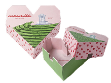 Three pink, heart-shaped gift boxes with a countryside scene and pink heart patterns; one box open to reveal a pink interior.